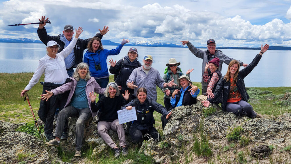Group of happy participants posing at Yellowstone Lake in a Paul Doss geology seminar.
