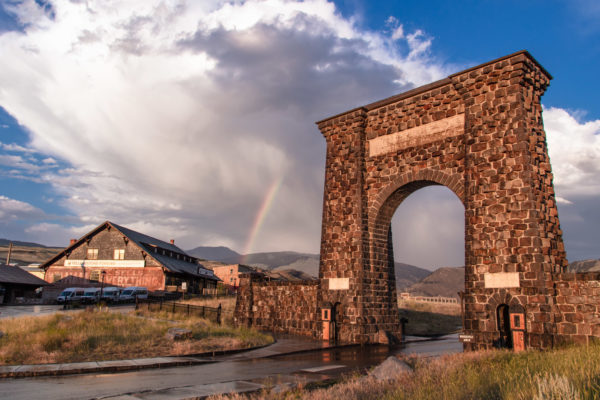 A rainbow appears between the iconic Roosevelt Arch and Yellowstone Forever store in Gardiner, MT.